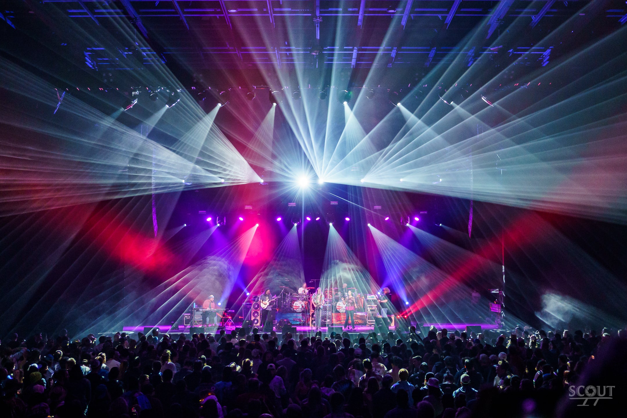 Dark Star Orchestra performs in blue light to a large crowd.